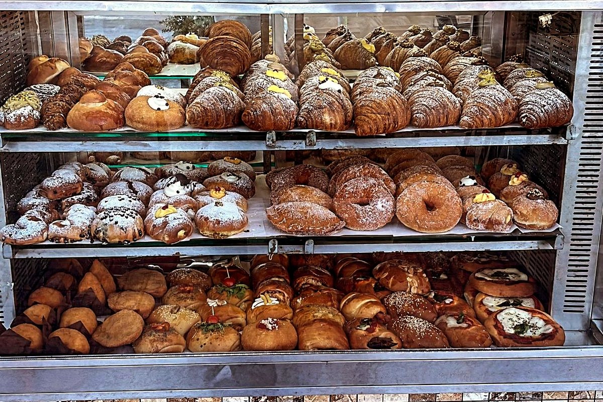 The pastry counter in the morning, three shelves of cornetti and rustici