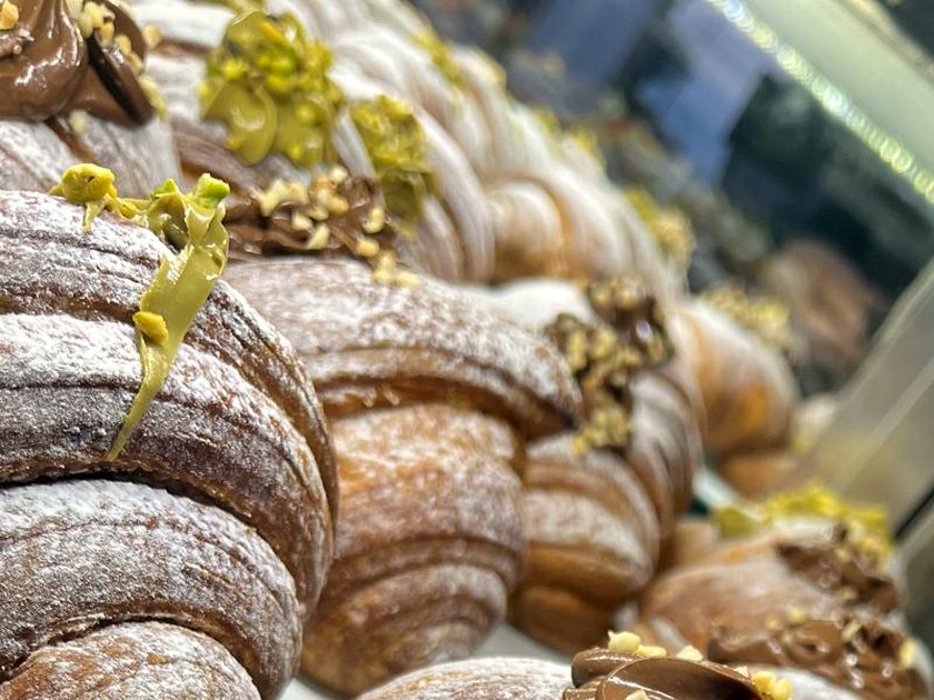 Sfogliatelle topped with pistachio cream and chopped pistachio, receding into the display case